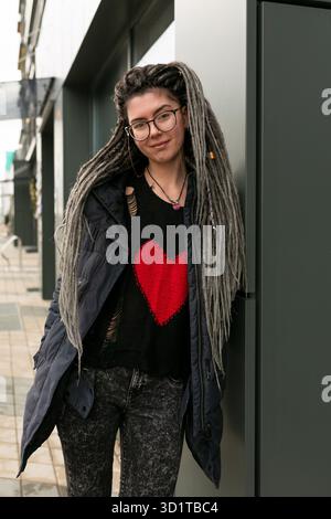 Photo on the street, young pretty informal woman with dreadlocks hairstyle smiling sweetly Stock Photo