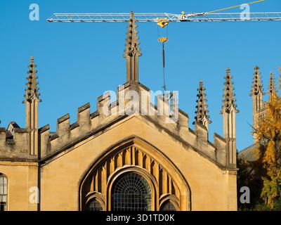 Giant crane looming over the spires of All Souls College.   All Souls College was founded by Henry VI of England and the Archbishop of Canterbury, in 1438.  Here we its ornate spires, viewed from New College Lane. The 21st century makes an appearance with a giant crane from a nearby construction site. Stock Photo