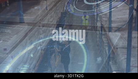 Scanning logistics manager in dark suit using handheld scanner inside warehouse with racks Stock Photo