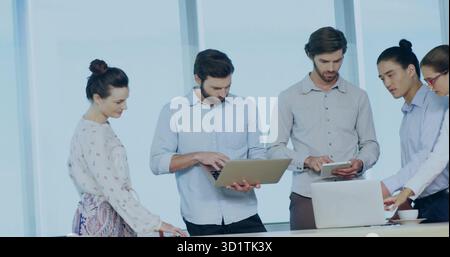Collaborating team in business attire reviewing content in meeting room, with laptops tablet Stock Photo