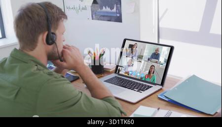 Conducting conference call on laptop while wearing headset at home desk, collaborating Stock Photo