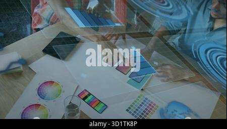 Working designers reviewing color charts, phone mockups and holographic overlays in meeting room Stock Photo