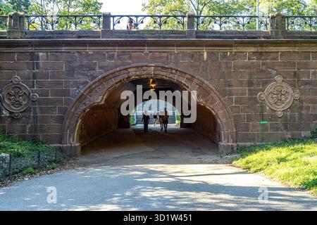 People walk through Trefoil Arch in Central Park, Manhattan, New York City. Stock Photo
