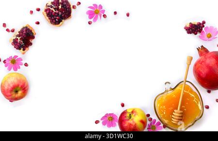 Honey in glass bowl, red apples, pink flowers, garnets, wooden honey dipper on a white background with space for text. Top view, flat lay Stock Photo