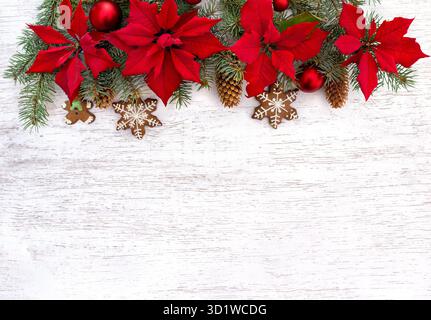 Christmas tree with Christmas balls, Christmas gingerbread, flowers of red poinsettia and cones spruce on white wooden background with space for text Stock Photo