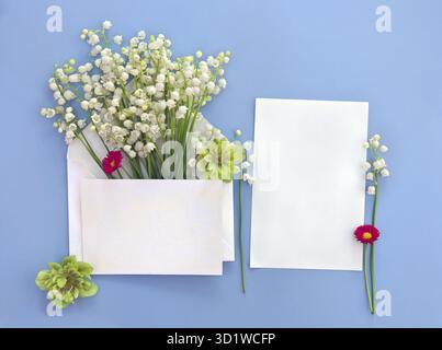 White flowers Lily of the valley ( Convallaria, May bells, may lily ), hellebores, english daisy, postal envelope with paper card note Stock Photo