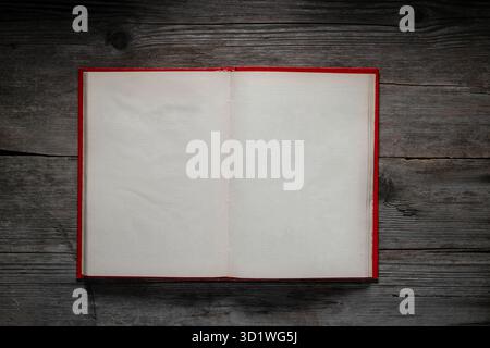 Open blank book on a rustic dark wooden background. Red cover, empty pages. Stock Photo