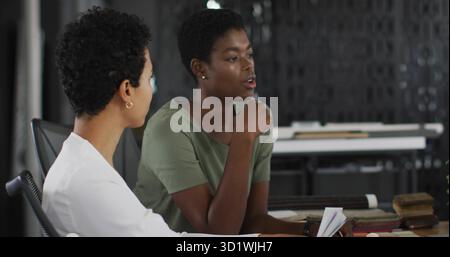 Two professionals collaborating in modern office meeting room, with documents and notebooks on desk Stock Photo