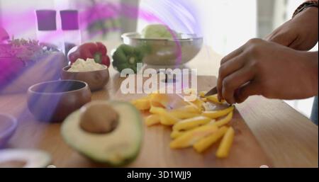 Chopping cook hands slicing yellow bell pepper with chef knife in kitchen avocado half, copy space Stock Photo