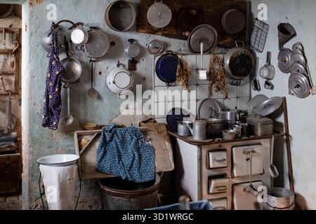 Vintage Rural Kitchen with Traditional Cookware and Rustic Wall Display in Abandoned Farmhouse Stock Photo