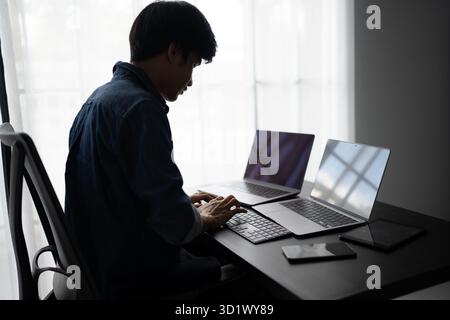 Asian man software engineer Working on Computer at office desk for writing program code IT Software Engineer finding errors tech Stock Photo