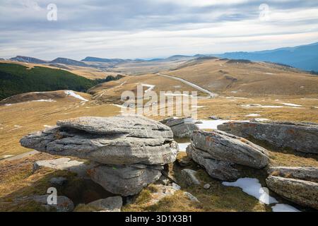 Rolling hills with rocks and patches of snow in Bucegi Mountains, Romania Stock Photo