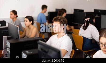 Clever focused male teenager solving tasks of computer science in the auditory Stock Photo