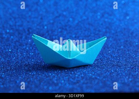 Paper boat on a bright blue background Stock Photo