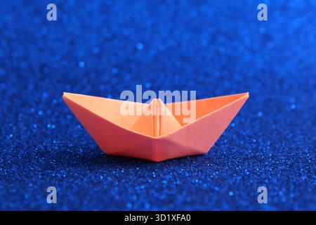 Orange paper boat on a bright blue background Stock Photo