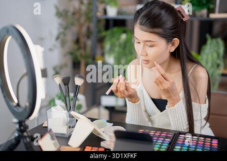 Asia woman beauty influencer makeup artist vlogger live streaming makeup tutorial on smartphone for social media Stock Photo