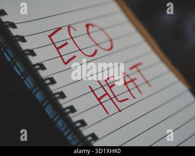 Side view of spiral notebook with ECO HEAT text, slightly tilted, blurred beginnings of letters, warm matte tones, sustainable energy concept, creativ Stock Photo