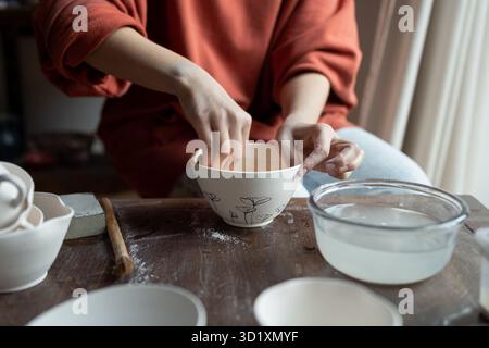 Close-up craftswoman hand working in art workshop on decorating plates made of pure porcelain Stock Photo