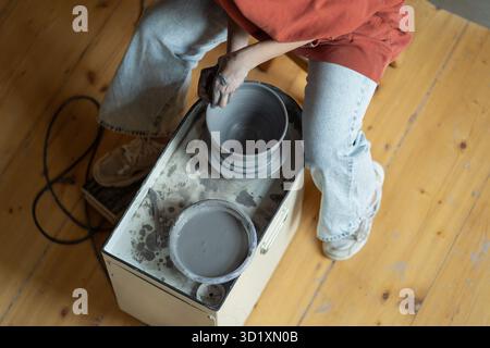 Top view of woman hands using potter wheel to shape handmade vessels made from natural clay Stock Photo