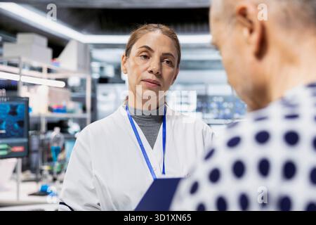 Woman pharmacology expert conduct tests on a senior man in modern research lab, observing side effects and chemical reactions. Scientist testing drug on patient to launch safe treatment. Stock Photo