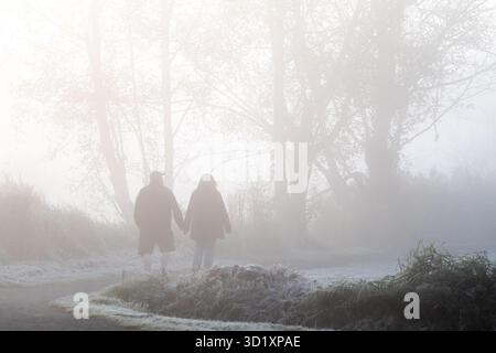 Couple walking hand in hand on foggy morning. Stock Photo