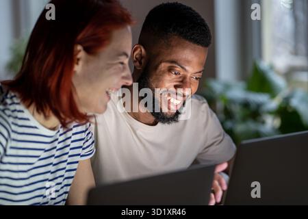 Happy man woman freelancers discussing project working on laptops looking at screen. Stock Photo