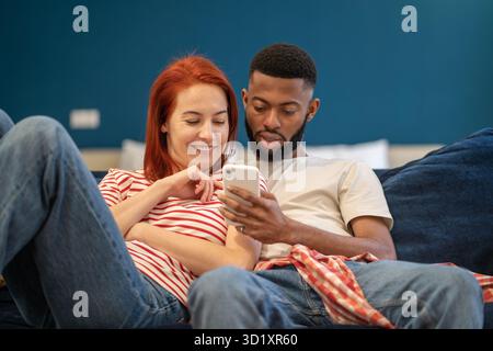 Guy and girl hug using phone. Woman and man watching videos, news from smartphone, smiling, laughing Stock Photo
