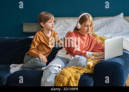 Children brother and sister sitting together with laptop on couch Stock Photo