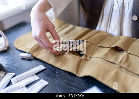 Female artist organizing desk and art supplies in studio Stock Photo