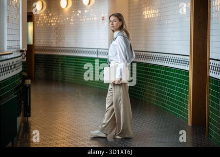 Businesswoman walks through office halls with laptop, immersed in tasks. Lady boss at work, startup Stock Photo