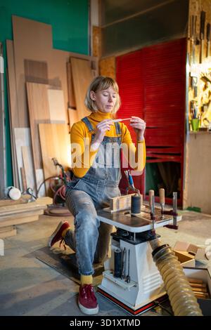 Skilled woodworker shape wooden knife blanks on lathe, carefully reviewing craftsmanship in studio Stock Photo
