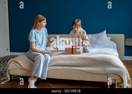 Curious kid son unwrapping gift box feeling excited getting present from caring loving mother Stock Photo