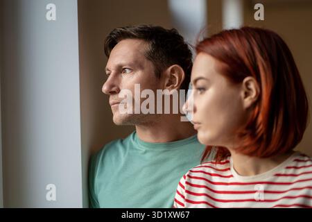 Pensive middle aged german man and woman looking out the window thinking having relationship problem Stock Photo