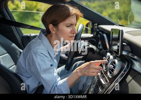 Bad smell from ac inside car. Woman driver feels an unpleasant odor after turn on air conditioning Stock Photo