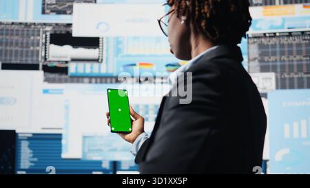 Business professional using isolated screen smartphone app to analyze performance dashboards metrics. Woman evaluating annual report data KPIs using mockup mobile phone, camera A Stock Photo