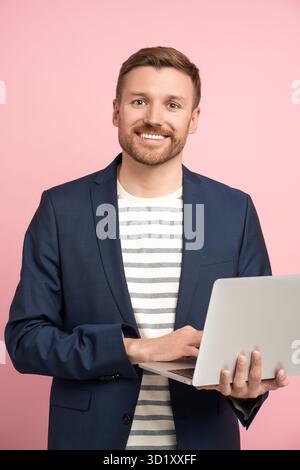Businessman with laptop isolated on pink. . Successful guy man smiling widely holding computer Stock Photo