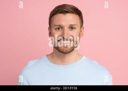 Portrait of caucasian bearded handsome man looking at camera smiling on pink studio background. Stock Photo