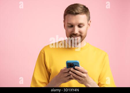 Man with phone, studio portrait. Guy uses smartphone, typing, texting, chatting in messengers online Stock Photo