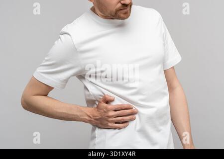 Closeup hand man touches unwell body side suffers from unbearable pain isolated studio background. Stock Photo
