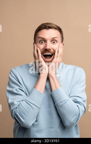 Happy surprised man looking at camera smiling with opened mouth wide spreaded eyes. Stock Photo