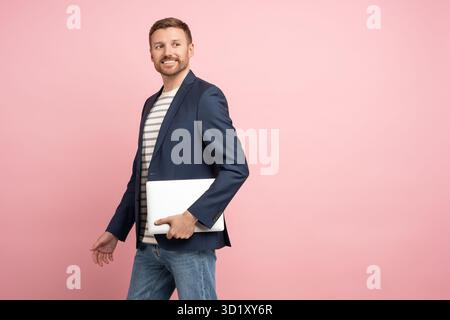 Man trader, crypto investor, entrepreneur, financier with laptop in hands on pink background. Stock Photo