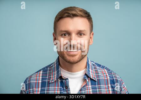 Portrait positive friendly caucasian bearded man looking at camera smiling on blue background. Stock Photo