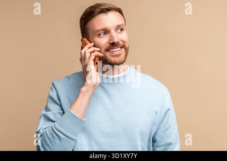 Happy smiling middle aged man talking calling phone on beige background looking aside. Stock Photo