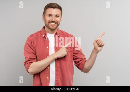 Excited happy positive young guy student pointing aside with fingers. Hand gesture, copy space Stock Photo