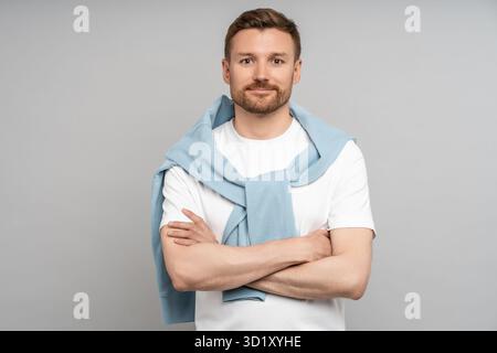 Smiling man with crossed arms looking at camera isolated on grey. Confidence, serenity, calm concept Stock Photo
