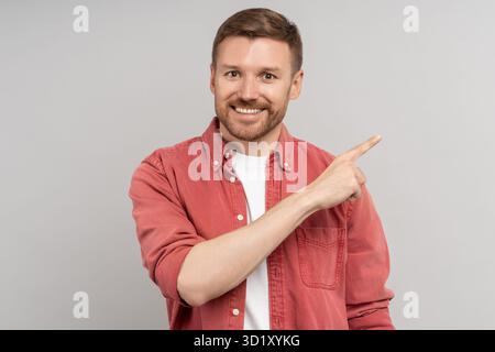 Pleased middle aged man smiling broadly points with index finger in right corner empty space for ad. Stock Photo