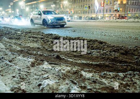 Snowstorm and thaw leave road covered in slushy snow dirt grime. Vehicles crawl through mess Stock Photo