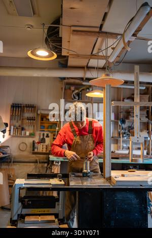 Carpenter prepares equipment for work. Man with wrench busy organizing workspace. Stock Photo