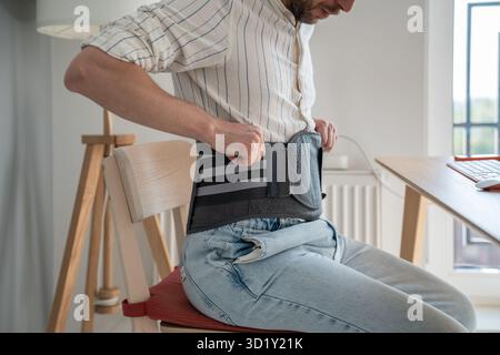 Man wearing back brace at home Stock Photo