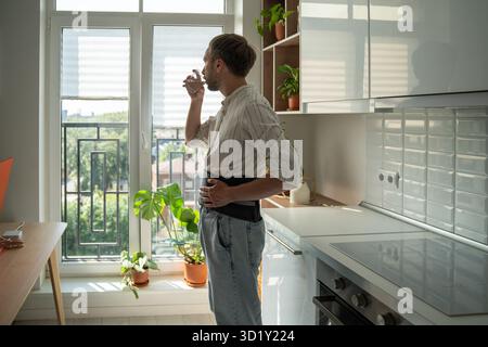 Young man wearing spinal brace drinking water recovering from back injury at home Stock Photo